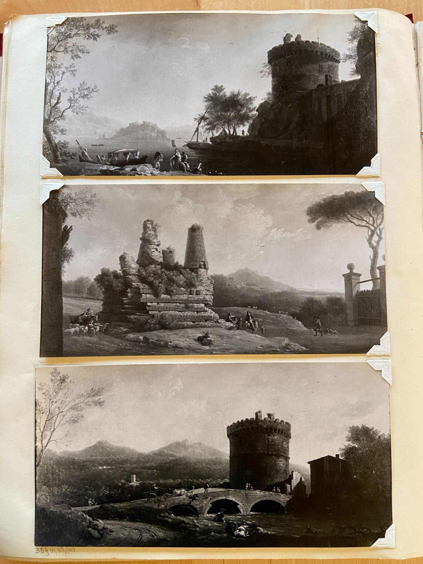 page of book with three horizontal black and white photos of landscape paintings inserted with photo corners